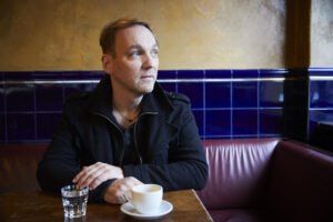 Arnold Kasar, Komponist von "Galaxy" und "Violet Sunrise", welche ruhige Sommer-Songs sind, sitzt in einem Café und schaut in die Ferne.