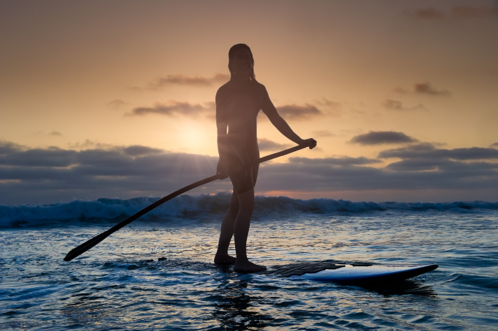 Zu sehen ist eine Person beim SUP fahren. Eine der vielen tollen Unternehmungen auf dem Wasser.