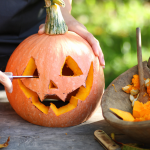 Man sieht wie in einem Kürbis zu Halloween ein Gesicht geschnitzt wird.