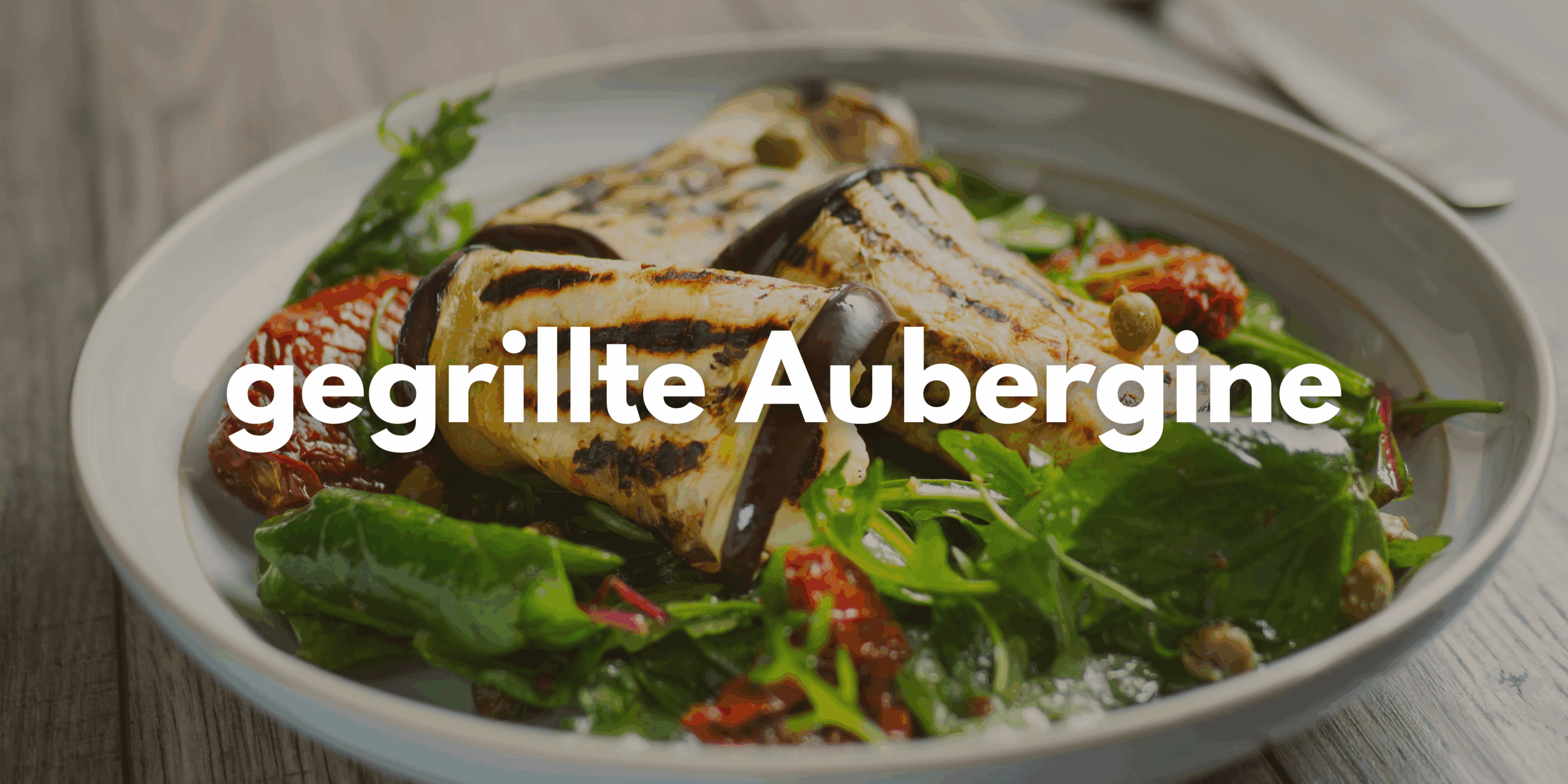 Zu sehen ist ein Teller gefüllt mit Salat und gegrillter Aubergine. Darüber der Schriftzug "gegrillte Aubergine".