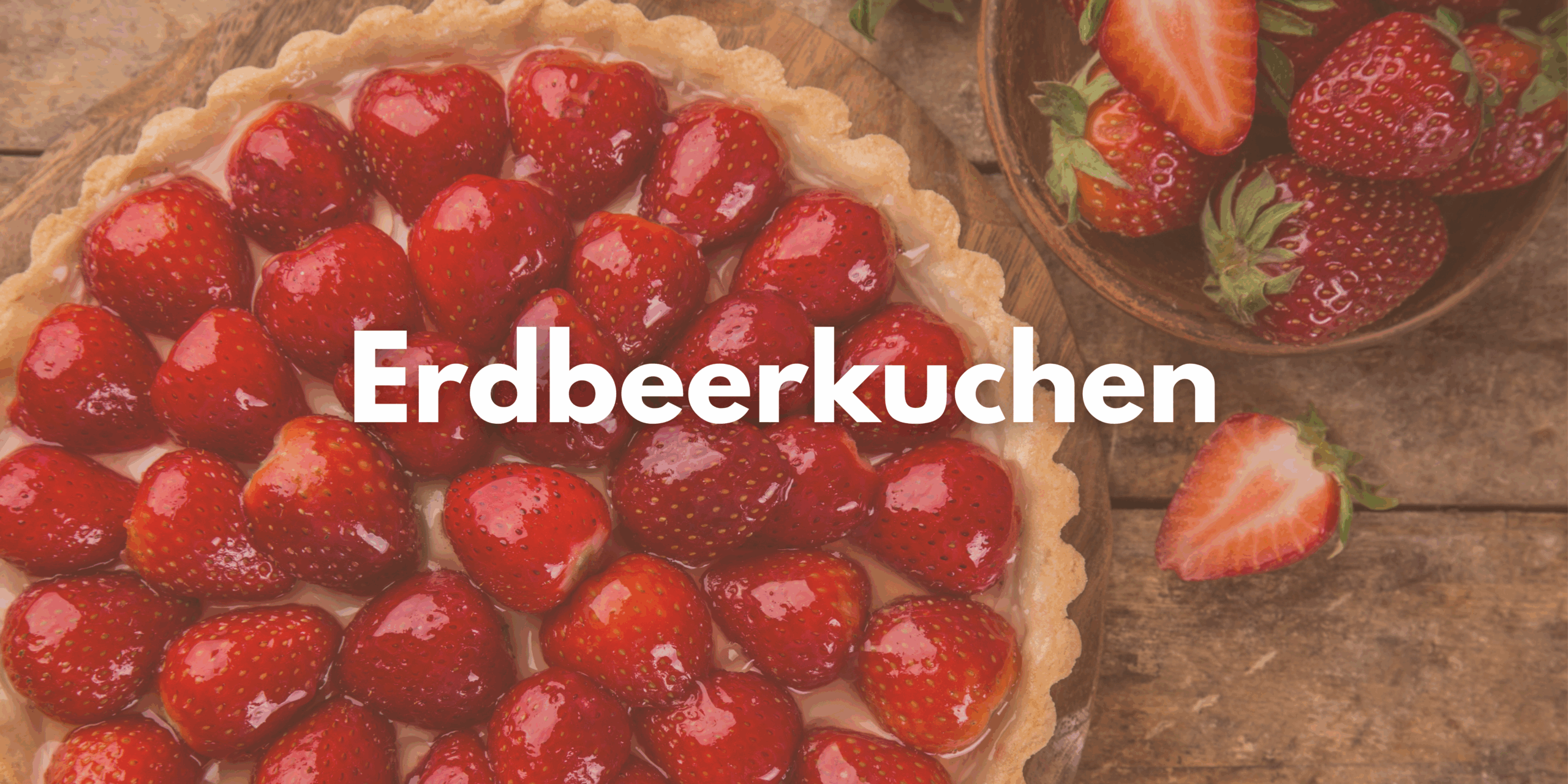 Man sieht einen Erdbeerkuchen und daneben einzelne Erdbeeren.