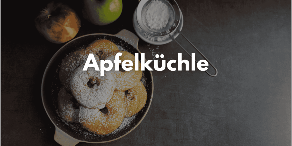 Auf dem Bild sind mehrere Apfelküchlein in der Pfanne zu sehen. Sie sind mit Puderzucker bestäubt.