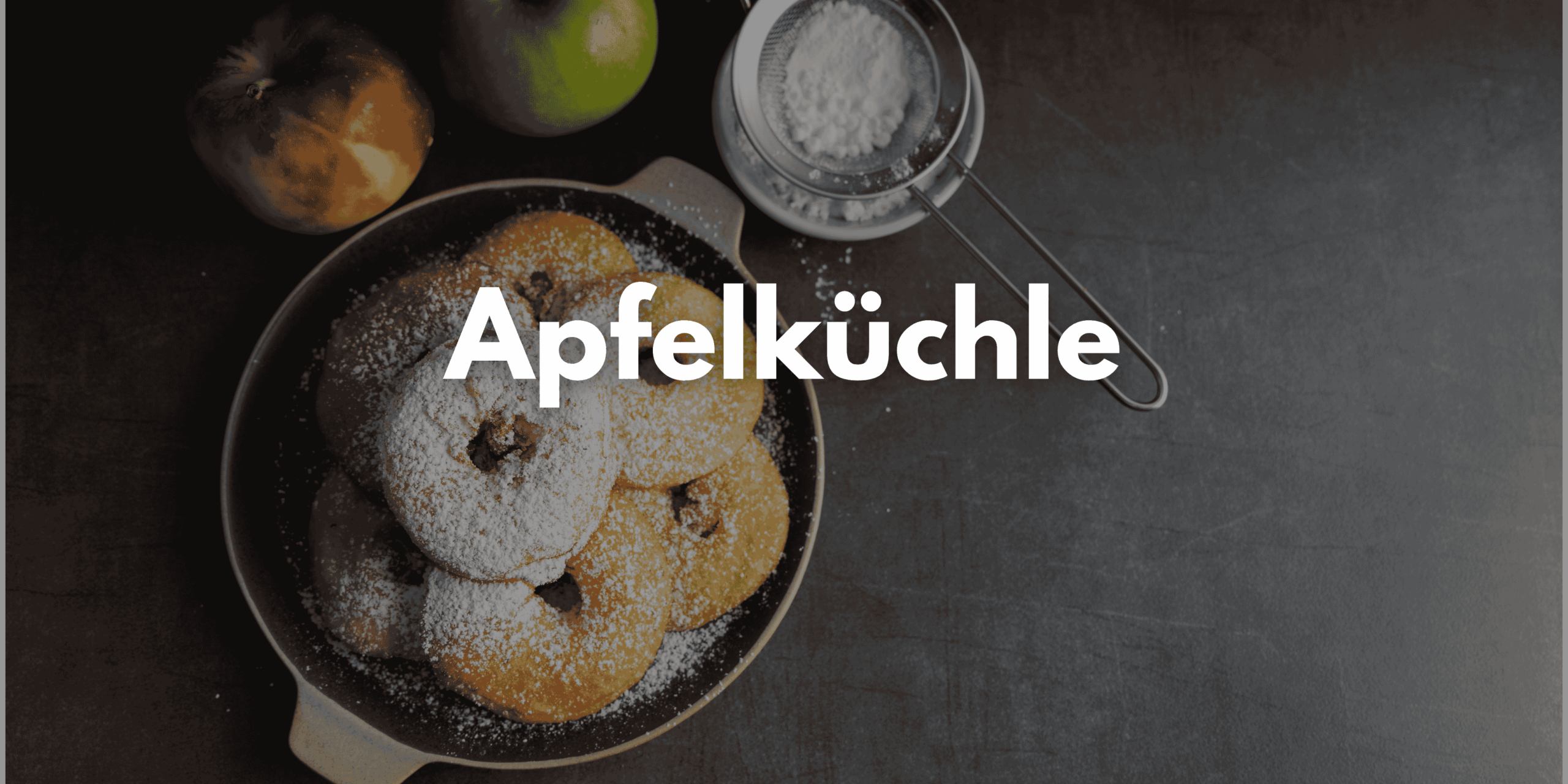 Auf dem Bild sind mehrere Apfelküchlein in der Pfanne zu sehen. Sie sind mit Puderzucker bestäubt.