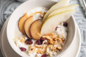 Bild, das eine Schüssel mit Birchermüsli und aufgeschnittenem Obst zeigt.